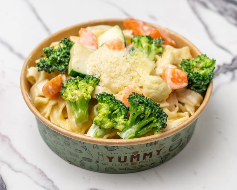 Creamy pasta with broccoli, carrots, and zucchini, topped with grated cheese in a Yummy Cheese Pasta bowl.